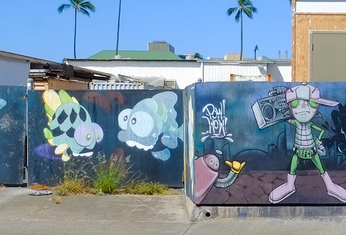 parts of two different murals, on the right a young man with a ghetto blaster on his shoulder beside a little robot and on the left, two fish 