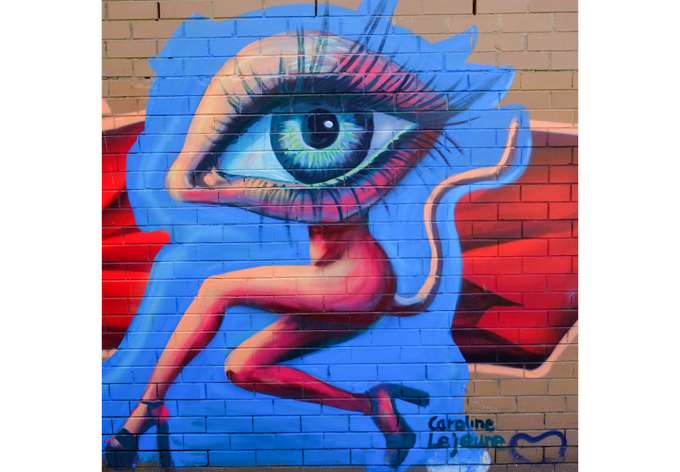 mural by Caroline Lejeune, wild looking over-sized eye atop a skinny naked body that even has a long tail. Naked except for the high heel shoes.