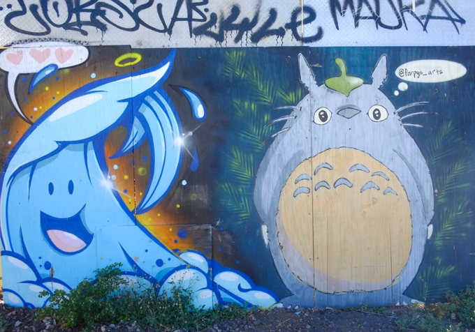 two street art pieces side by side, a blobby creature by far_pys on the right and a blue wave of water with a face on the left