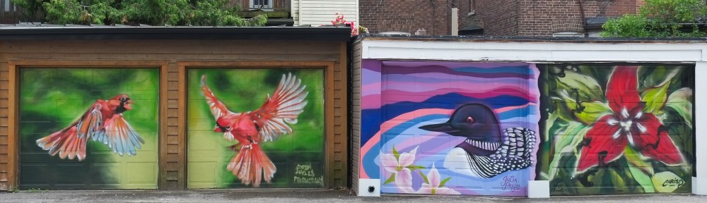 murals that have been painted on a row of garages, two red cardinal birds in flight, a loon swimming in the water