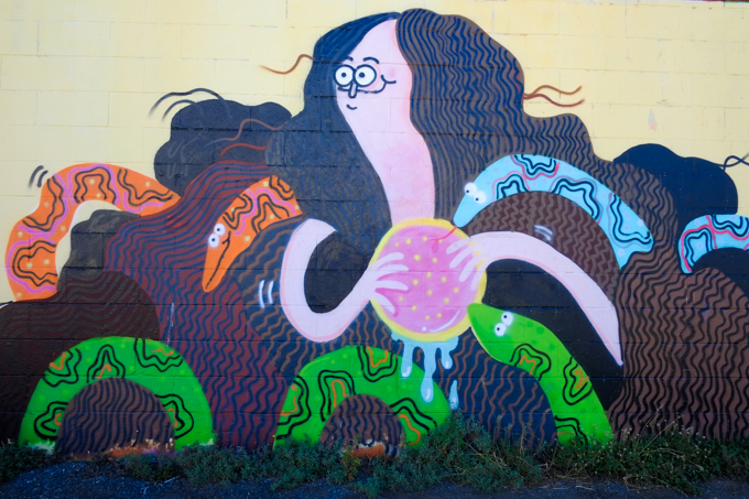 street art by Jay Howell in Honolulu, female figure with long dark brown hair with at least three snakes in it.  An orange snake, a blue snake and a green one.  