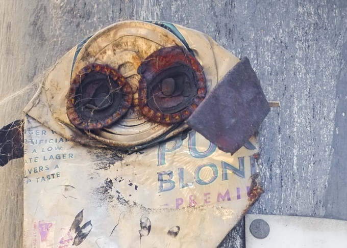 Junky graffiti made of crushed beer can, with bottle tops for eyes