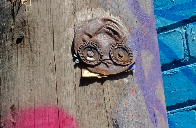 Junky graffiti made of crushed tin can, with bottle tops for eyes