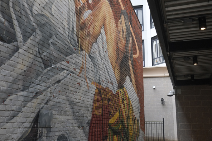 street art mural in Lynn Massachusetts by Fonki, woman lying in a bed 