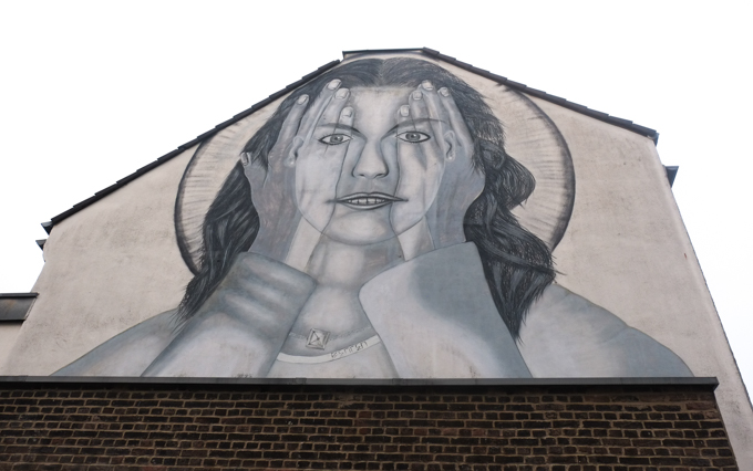 urban art, street art, in Cologne Germany, near Ehrenfeld station, large monotone mural, Any Europeans should see behind the wall" by the artist Benten, woman holding hands up in front of her face