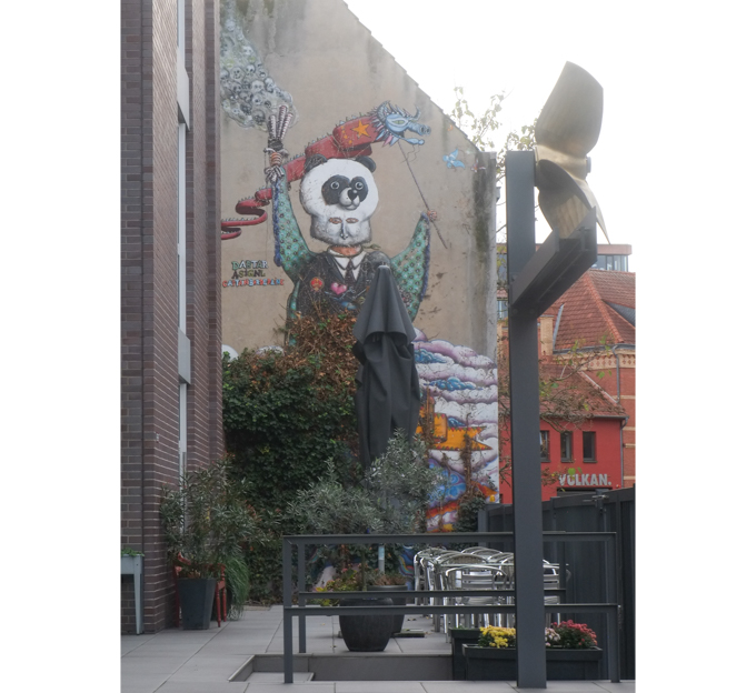 restaurant patio in front of a wall with urban art, street art, in Cologne Germany, near Ehrenfeld station, A Chinese Fairy Tale" painted by the street art crew Captain Borderline, A.Signl and Dabtar, dragon puppet, panda mask,