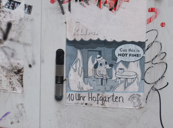graffiti, cartoon picture of dog sitting on a chair, by a table with a mug on it, flames around it, text balloon that says cuz this is not fine