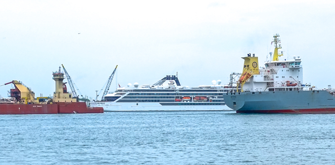 boats on the Detroit River, a rusty red and yellow boat, a cruise ship, and a navy boat