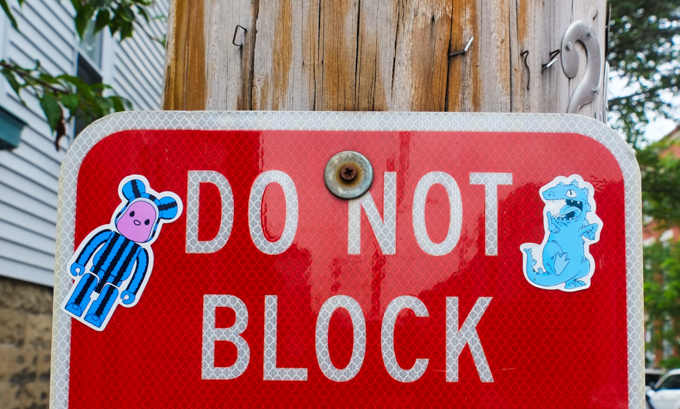 little stickers on a red do not block street sign