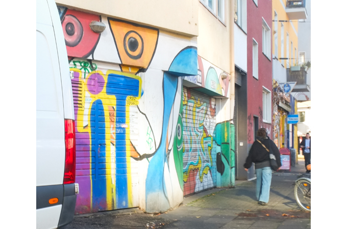 person walking past urban art, in Cologne