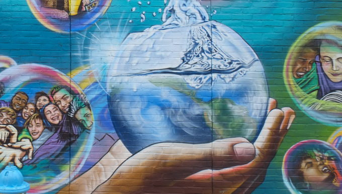 hand holding a glass globe full of water, street art mural