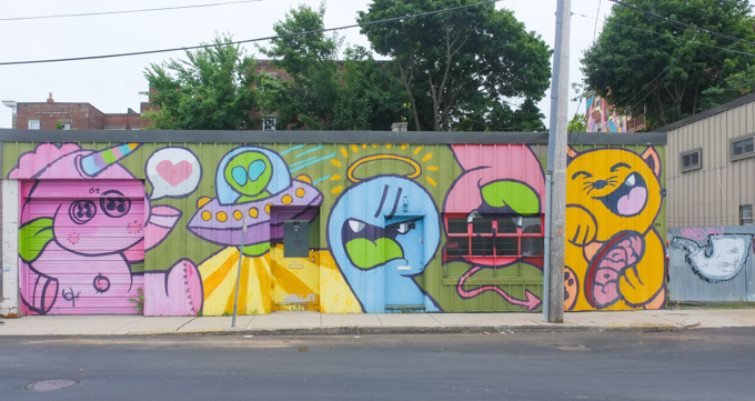 part of Golden 305 mural in Salem, pink unicorn, yellow cat, blue face with a yellow halo, alien in a small spacecraft