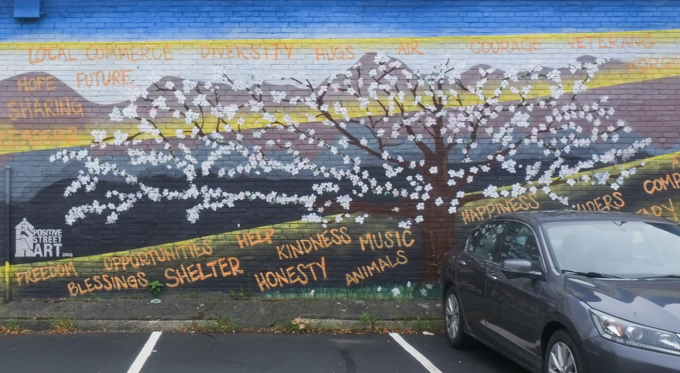 mural, spring tree is full of white blossoms with words like, honesty, shelter, blessings, freedom, alive, sharing, happiness, music, animals,