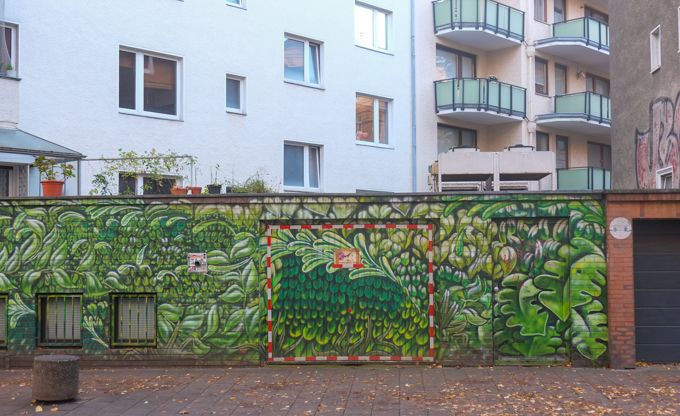 Green botanical and leaf motif wrapping around the base of the building and fence