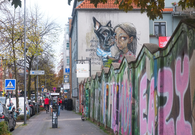urban art, street art, in Cologne Germany, near Erheneld station,by Herakut, a girl and her dog. dog is wearing blue and white striped t shirt