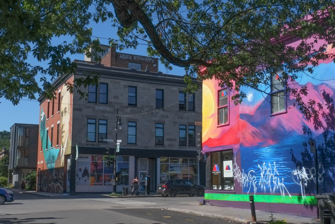 at Blvd Saint Laurent and Rue Marie-Anne, 2 buildings on opposite corners, each with a street art mural on it