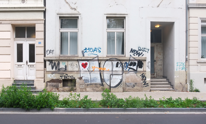 scrawl graffiti on a white building in Bonn, large M and e with a red heart