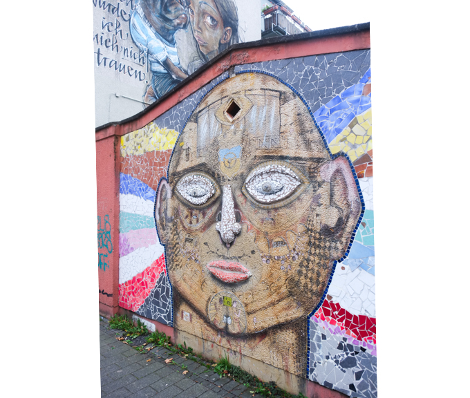urban art, street art, in Cologne Germany, near Ehrenfeld station, 3D mosaic head by Captain Borderline, big white eyes and nose, red lips, closed mouth, big ears, bald
