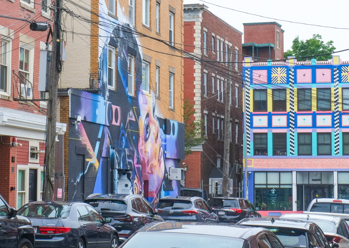 Mr. Cenz mural in Salem, woman's face on a building adjacent to one whose facade has been painted in graphic geometric shapes