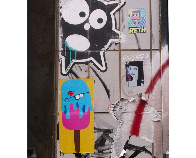 urban art, street art, in Cologne Germany, near Ehrenfeld station, Four little bits and pieces - A NanE popsicle with a goofy toothy expression. A black and white Bustr who seems to be gaping wide mouthed at the tiny woman's portrait. The latter was made by Henry Paulson who seems obsessed with three or four young woman whose very similar portraits can be seen in a LOT of places. Last, top right is Little Vandal Cube by Reth.