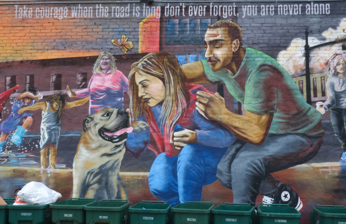 Mural, couple with a dog, with many people around them, with text, Take courage when the road is long don't ever forget, you are never alone. by Positive Street Art members