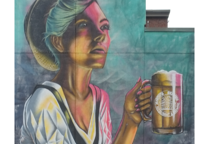 Martha's Muse, was painted by Manuel Ramirez from Positive Street art. shows woman sitting at a table drinking beer