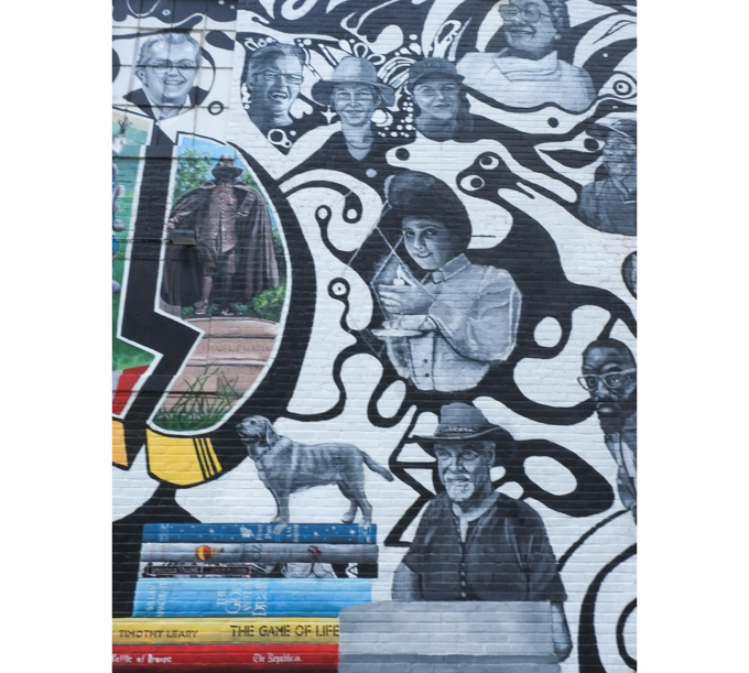 a pile of books, a bronze statue, and many portraits, part of mural in Springfield Massachusetts, with word Springfield in capital letters and in colour, with illustrations inside the letters and black and white images of people and things associated with the city