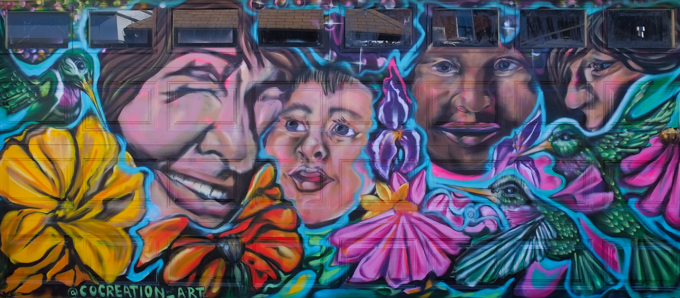 street art mural on garage door in Miriam Garfinkle Lane, by Danielle Hyde, faces, hummingbirds and flowers