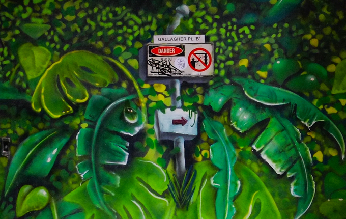 part of mural, lots of tropical type leaves surrounding a real danger sign