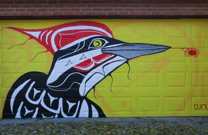 street art mural on garage door in Miriam Garfinkle Lane, by DJNU, a bird with a crested head