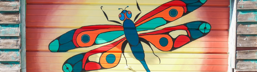 part of a mural by Christine Whiteduck on a garage door in Miriam Garfinkle Lane, a large colourful dragonfly