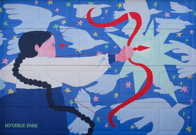 street art mural on garage door in Miriam Garfinkle Lane, by Hyunsun Park, female archer with red bow and arrow, taking a shot, concentrating