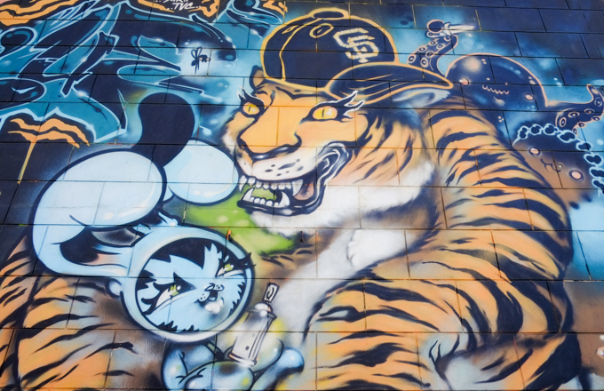 part of a mural by Persue, Dave Persue Ross, sharks vs tiger, tiger is holding a Bunny Kitty who in turn has a spray paint can in it's hand.  Tiger is wearing a cap with a San Francisco Giants logo.  There is also an octopus with a knife