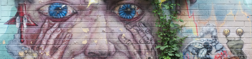 blue blood shot eyes on a face where hands are covering cheeks, part of a mural by scribe