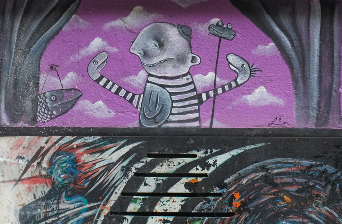 two halves, divided horizontally, upper half is painting by Lea, purple sky, man with small hat, smiley face on front of his shirt, smile on his face, but with hands that look like snake heads