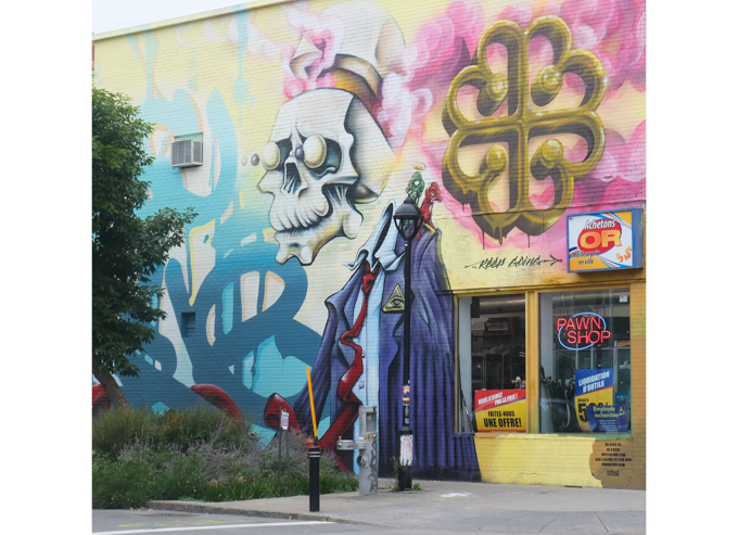 Part of a larger mural originally painted by Scaner in 2014, skull showing, a skeleton with clothes, upright and walking. Wearing blue jacket, white shirt, and red tie, also wearing a hat